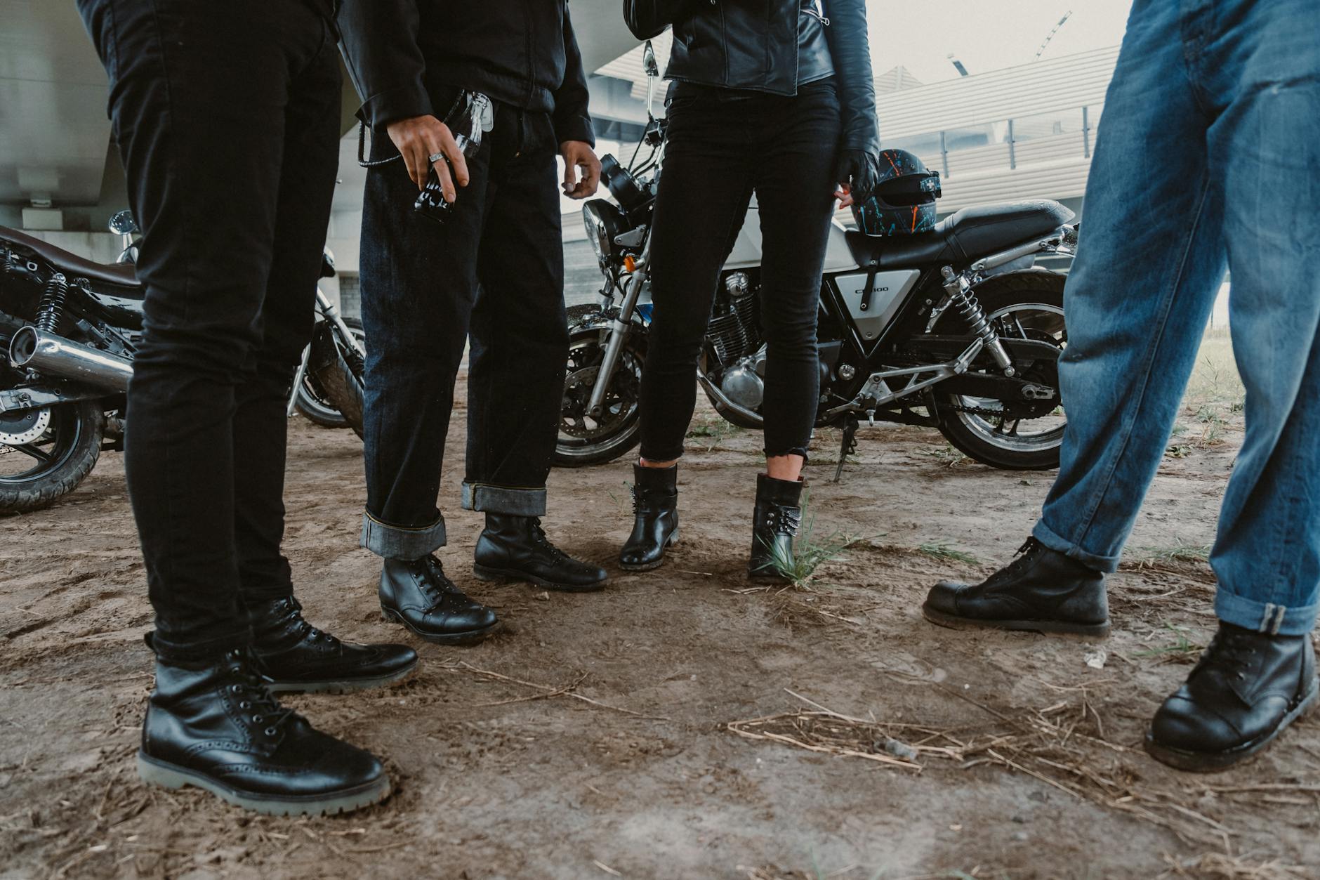 people wearing black leather boots standing near parked motorcycles